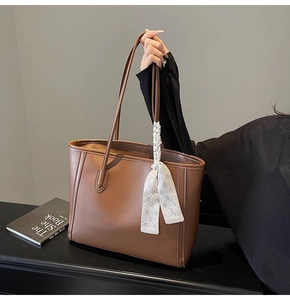 Detailed view of brown leather tote bag with elegant checkered scarf on the handle