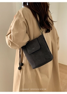 Détail du sac cabas en daim gris foncé avec cordon de serrage sur manteau beige