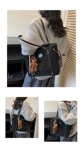 Detail of black tote bag with white contrast stitching and a cute bear bag charm