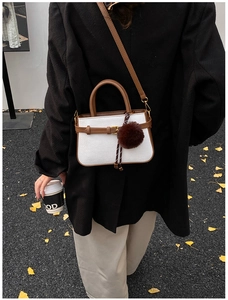 Detail view of retro bucket bag with woven texture, leather trim and fur ball charm
