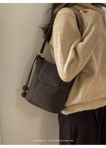 Détail d'un sac seau rétro marron foncé orné de pendentifs à double boule originaux