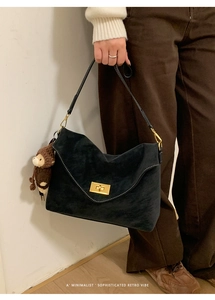 Macro shot of minimalist suede handbag with gold twist lock and monkey charm