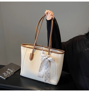 Detail of off-white leather tote bag with dark brown trim and plaid silk scarf decoration