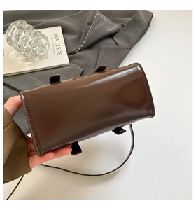 Detail of the dark brown shiny leather crossbody bag base and side stitching quality
