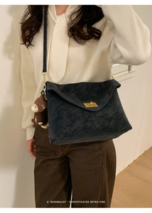 Detail of retro black suede crossbody bag with gold buckle and plush monkey charm