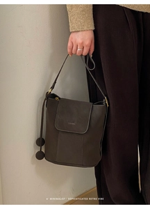 Détail d'un sac seau vintage marron foncé avec texture lisse et pendentif à boule