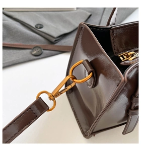 Detailed close-up of glossy brown faux leather handbag with premium gold metal hardware