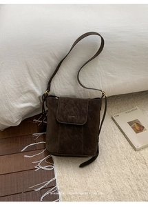 Gros plan détaillé du sac seau en daim marron foncé avec boucle dorée et logo de marque