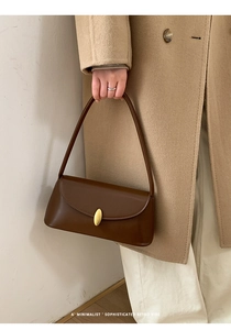 Close-up of brown leather baguette bag featuring a sleek golden oval metal buckle