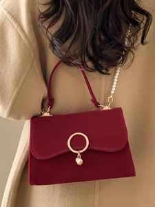 Elegant dark red velvet handbag with golden ring and pearl chain strap on model