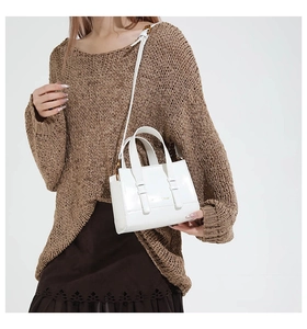 Detail of white glossy leather mini tote with gold hardware and adjustable strap