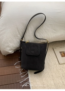 Gros plan du sac seau en cuir gris mat avec boucle métallique dorée au style minimaliste