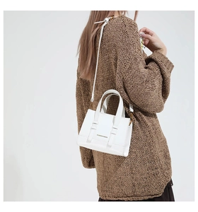 Close-up of minimalist white leather crossbody bag with Fashion & Bags text on brown sweater