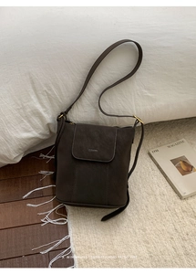 Détail du sac seau en cuir marron foncé avec logo de marque et garnitures dorées