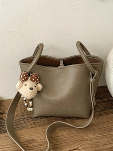 Sac seau en cuir vert olive avec texture grainée, pendentif ours et bandoulière