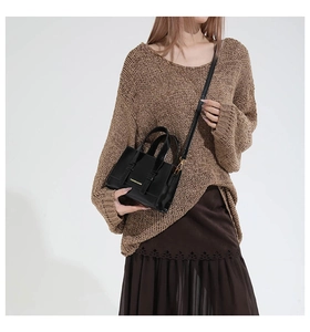 Fashionable black crossbody bag with gold hardware shown on a model in autumn knitwear