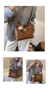 Detail of dark brown leather hobo bag with gold chain strap and cute bear charm