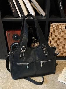 Classic black leather tote bag with dual front zippers and silver hardware in lifestyle setting