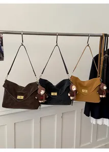 Detailed view of suede-textured flap bags in brown and black with gold hardware accents