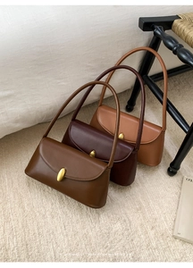 Three retro faux leather baguette bags in shades of brown with golden oval turn-locks