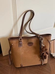 Brown vintage suede tote bag with plush bear charm and minimalist top handle design
