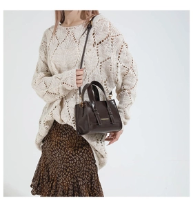 Detail of dark brown leather mini bag with gold hardware and dual top handles