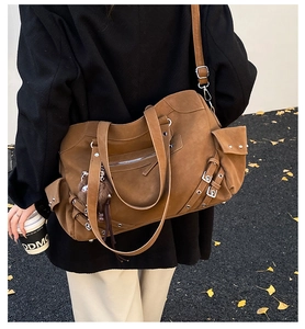 Detail view of large brown suede tote bag with metal buckles and plush charm accessory