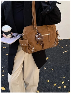 Detail of vintage brown suede tote bag with multiple metal buckles and a leopard monster charm