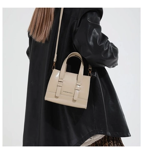 Close-up of beige glossy crossbody bag with Fashion & Bags text on a leather jacket