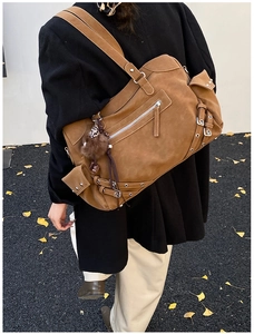 Detail of vintage brown suede tote bag with metal zippers and plush charm on shoulder