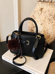 Minimalist black woven bucket bag for women with golden hardware and plush charm