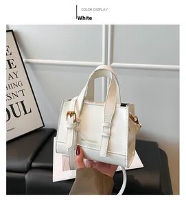 White faux leather crossbody bag detail with golden hardware and fashion logo text