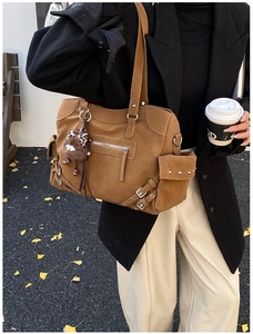Close-up of retro large brown tote bag with metal buckles and plush charm on handle