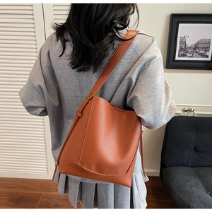 Close-up of caramel bucket bag with lychee grain texture and curved stitching detail