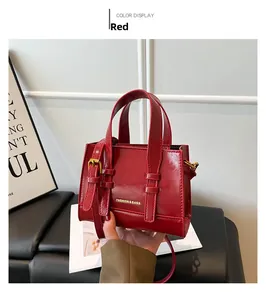 Detail of red glossy leather handbag with gold adjustable strap and fashion lettering