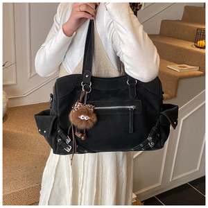 Detailed view of black large capacity tote bag with metallic zippers and plush monster charm