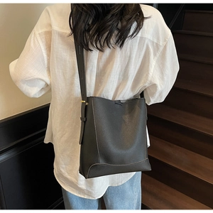 Rear view of black bucket bag with lychee pattern on model walking up stairs