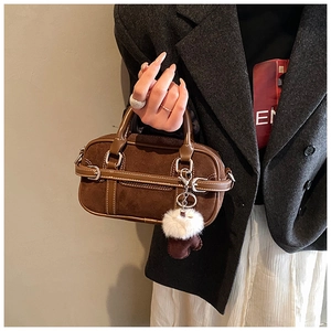 Détails d'un sac à main en daim marron avec pompon en peluche et coutures précises