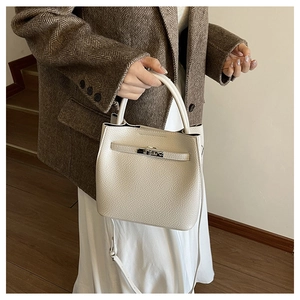 Close-up of white textured leather bucket bag featuring silver twist lock and handle