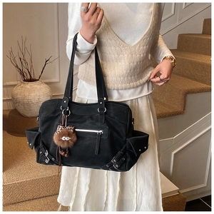 Detail of black tote bag featuring metallic eyelet straps and a cute brown plush charm