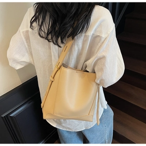 Detail of soft cream yellow bucket bag with adjustable shoulder strap and reinforced base