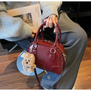 Deep red Boston bag detail with embossed lettering and a cute brown plush dog charm