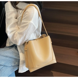 Close-up of beige lychee grain leather bucket bag with long shoulder strap detail