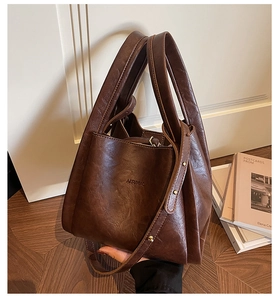 Detail of vintage brown tote bag with textured finish, brand logo, and golden buckle