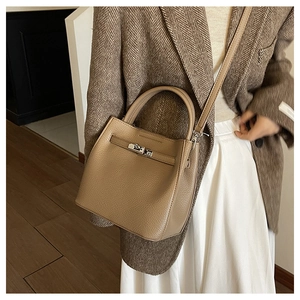 Close-up of pebble leather texture and metallic clasp on a khaki crossbody bag