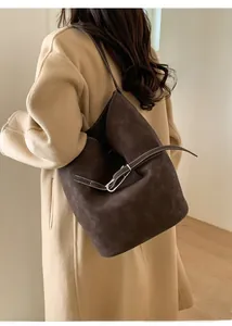 Détail du sac seau en daim marron foncé avec boucle en métal argenté et bandoulière fine