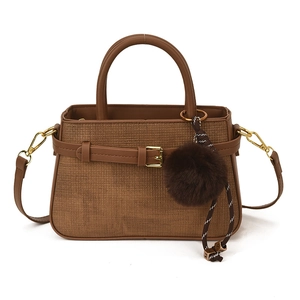 Retro brown bucket bag with woven texture, top handle, and fuzzy pompom charm detail