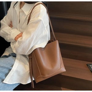 Close-up of brown lychee grain bucket bag showing soft PU leather texture and shoulder strap