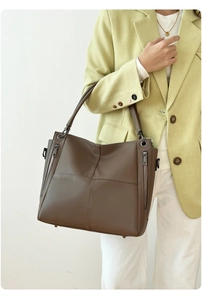 Detail of dark brown lychee leather tote bag featuring cross stitching and side zippers