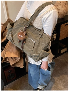 Detail of army green vintage tote bag with metal zippers and cute monster charm